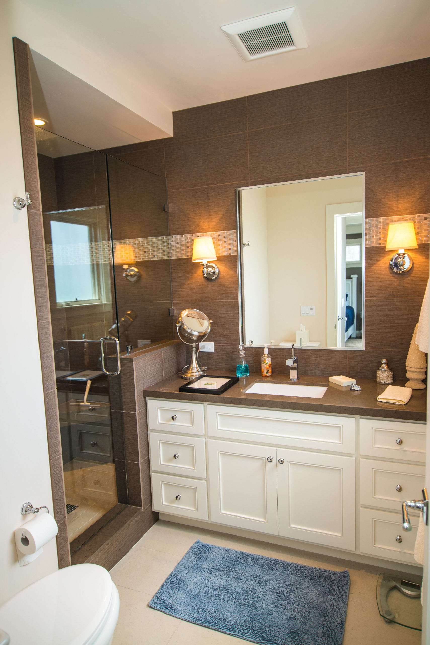 Modern bathroom with white vanity, large mirror, and glass shower enclosure.