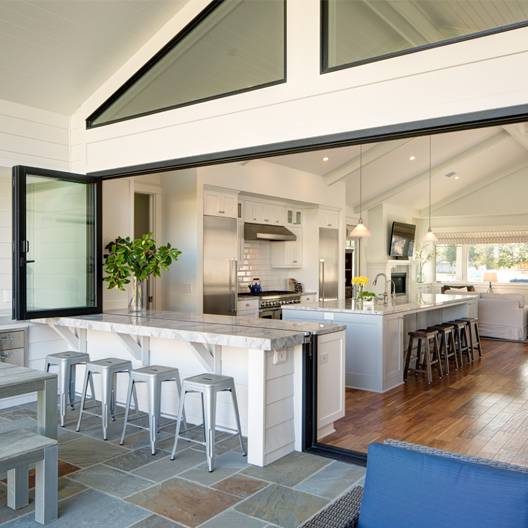 Modern open kitchen with marble island and bar stools.